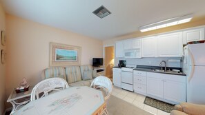 A compact living space with a kitchenette, a dining area, and a seating area with a television. - Driftwood Landing 10- Isles of Capri Vacation Resort (Naples)