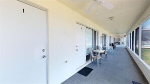 Guest rooms line the corridor, leading to a cozy seating area with tables and chairs.