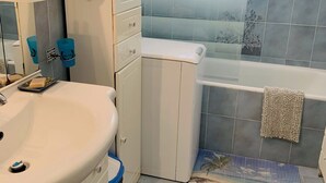 Een badkamer met een witte wastafel, een bad en een raam.