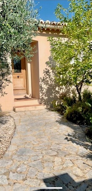 Stroll through lush greenery to a charming Mediterranean-style entrance.