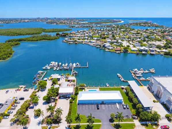 A marina with boats docked, a large building, and a clear view of the surrounding water and land. - Driftwood Landing 13- Isles of Capri Vacation Resort. (Naples)