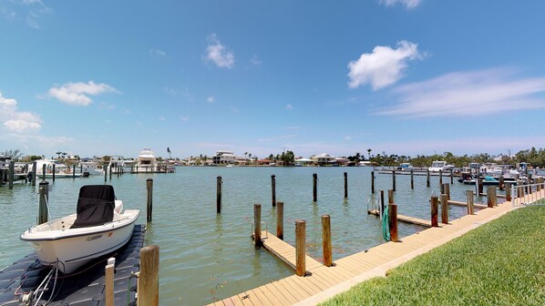 A marina with boats docked, a wooden dock, and a clear sky.