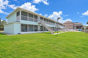 A two-story motel with a covered outdoor seating area and a staircase leading to the upper level.