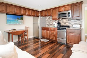 Una cocina con gabinetes de madera, un refrigerador de acero inoxidable, un microondas y una estufa.