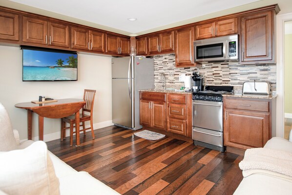A kitchen with wooden cabinets, a stainless steel refrigerator, a microwave, and a stove.