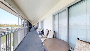 Un balcon donnant sur des bateaux, avec des chaises et une table.