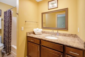 A bathroom with a sink, mirror, towel rack, and a shower curtain.