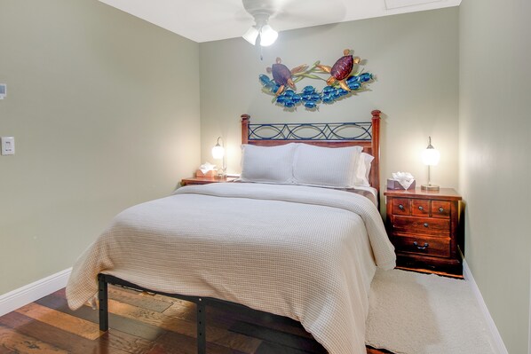 A bedroom with a bed, nightstands, a dresser, and a decorative wall piece.