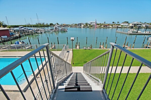Un puerto deportivo con barcos, piscina y una escalera que lleva a una zona cubierta de césped.