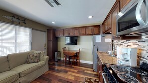 Une cuisine compacte avec des meubles en bois, une cuisinière encastrée et un coin repas comprenant une table et des chaises.
