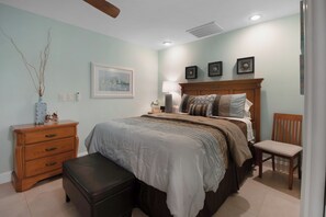 A bedroom with a bed, a nightstand, a chair, a dresser, and a painting on the wall.