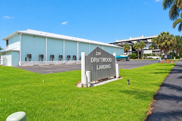 A building with a sign reading '220 DRIFTWOOD LANDING' and a parking lot in front.