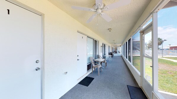 A corridor with doors numbered 1 and 2, a ceiling fan, and a view of the outside.
