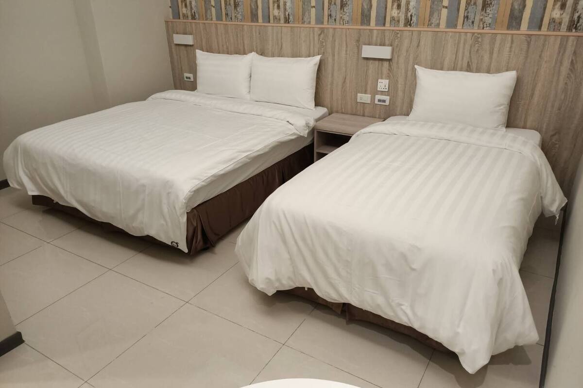 A hotel room with two beds, a small bedside table, and a mirror.