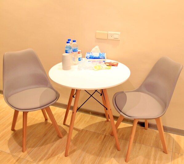 Uma mesa redonda branca com duas cadeiras cinzentas, um estojo de lenços de papel, água engarrafada e lanches.