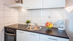 Une cuisine moderne avec des armoires blanches, un évier en acier inoxydable, un four encastré et une machine à café.