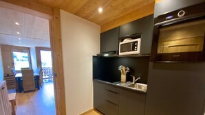 Een kleine keuken met een magnetron, oven en spoelbak.