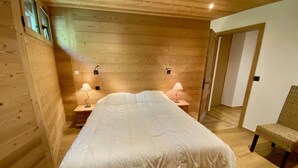 Een kamer met houten lambrisering, een groot bed, twee bedlampen en een stoel.