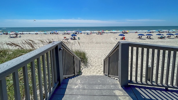 A wooden staircase leading to a beach with umbrellas and beach chairs. - Tidemaster. 3 bedroom oceanfront condo 1st floor with elevator. Pool. (North Myrtle Beach)