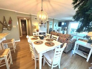 A dining area with a round table, white chairs, and a chandelier.