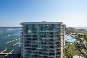 A high-rise hotel with multiple balconies overlooking a marina and ocean.