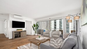 A modern living room with a sofa, coffee table, and television. - Gorgeous 2-bedroom listing! Half-block from Waikiki Beach! (Honolulu)