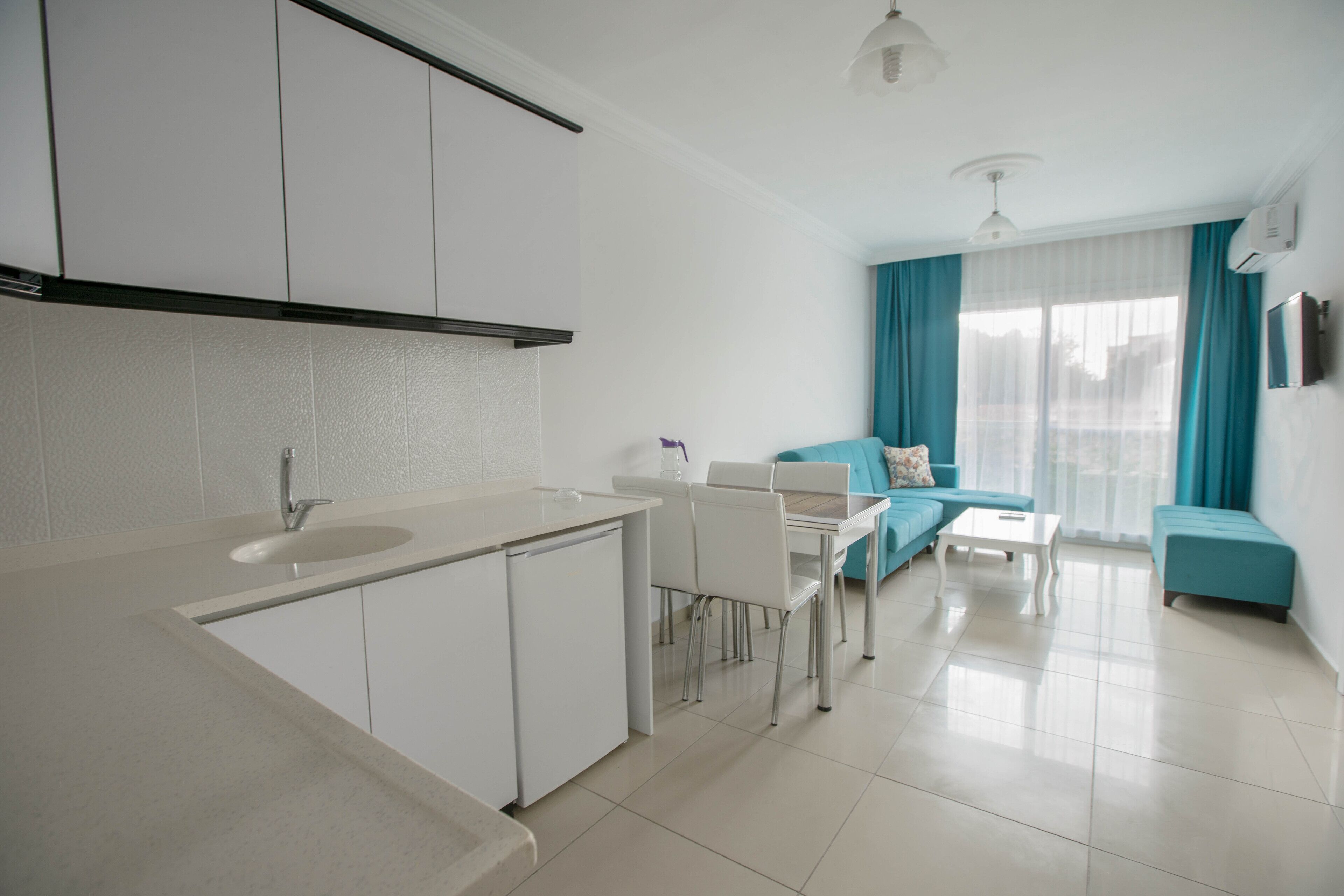 A modern kitchen with white cabinets, a sink, and a dining area with a table and chairs.