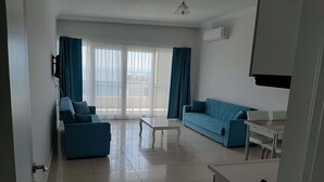 Un saló modern amb un sofà blau, una taula de cafè blanca i una zona de menjador amb taula i cadires.