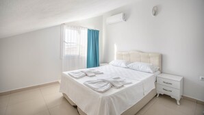 Un dormitori amb un llit, una tauleta de nit i una finestra amb cortines.