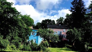 Un immeuble d’habitation à la façade bleue, entouré d’une végétation luxuriante et d’arbres.