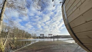 Une jetée en bois s’étendant sur un lac paisible, avec deux chaises et un banc placés sur la jetée.