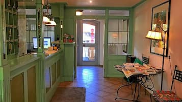 Una cocina con armarios verdes, una mesa de comedor con sillas y un refrigerador.