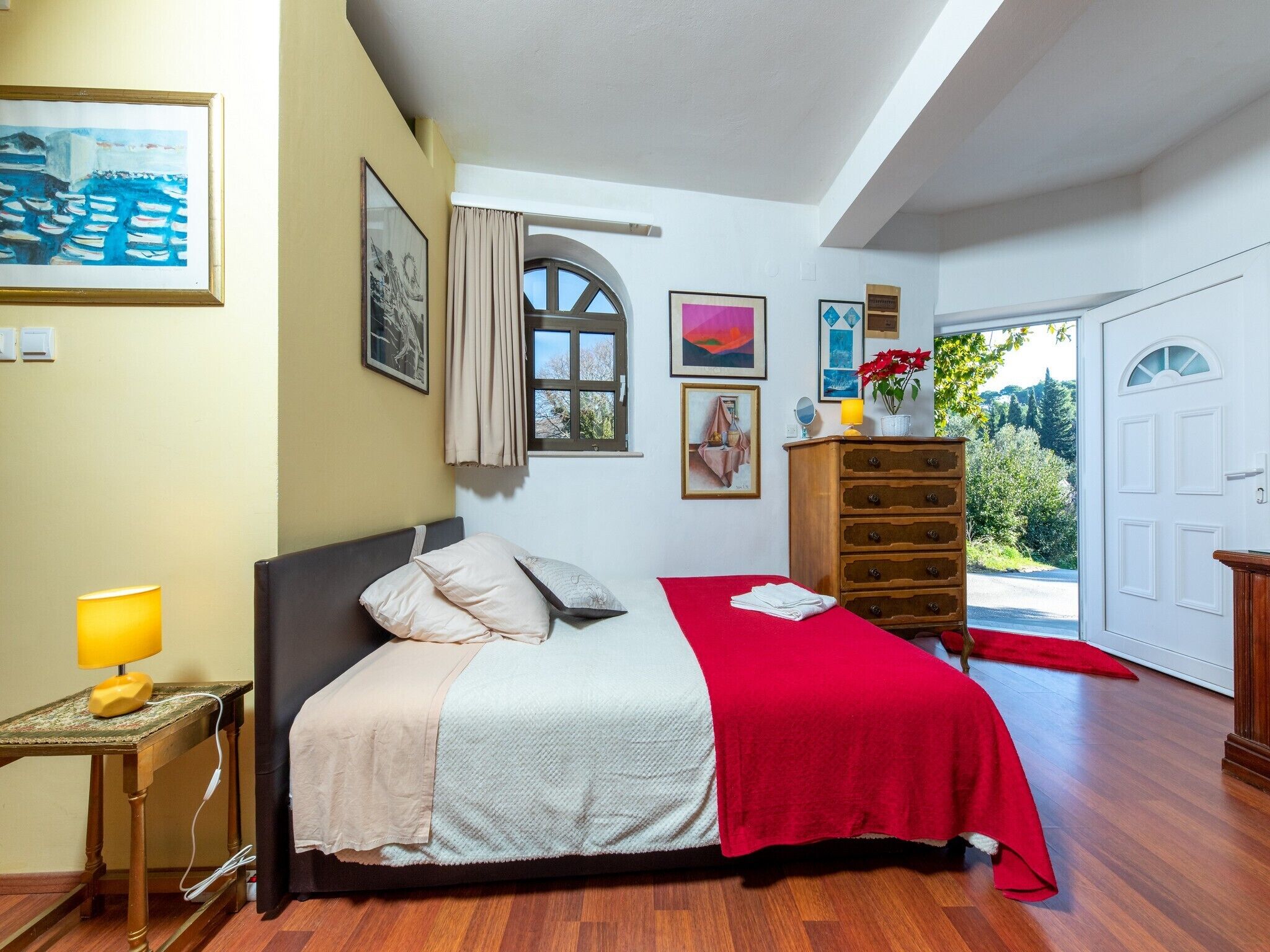 Een slaapkamer met een bed, een kaptafel, een raam en kunst aan de muren.