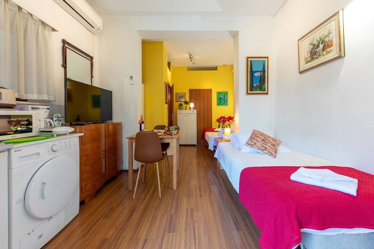 Een kleine hotelkamer met kitchenette, een eethoek, een bed en een badkamer.