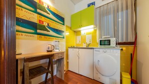 A compact kitchen with a washing machine, a coffee maker, and a microwave on the countertop.
