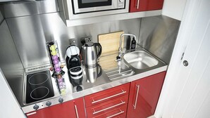 A compact kitchen with stainless steel appliances, a microwave, a kettle, and a sink. - Piper's Hut - Central apartment  (Portree)