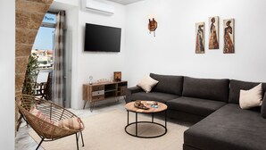 Una sala de estar moderna con un sofá, una mesa redonda de centro, una silla de mimbre, un televisor de pantalla plana y obras de arte en la pared.