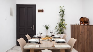 Un comedor con mesa de madera, sillas color beige y una planta en maceta.