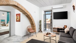 Una sala de estar moderna con un arco de piedra, un televisor de pantalla plana, un sofá, una mesa de centro y una silla de mimbre.