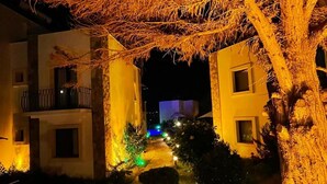 A nighttime view of a building with illuminated pathways and trees. - The Mara Suite (Bodrum)