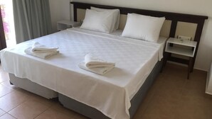 A neatly made bed with white linens and pillows, a bedside table with a lamp, and a window with curtains. - The Mara Suite (Bodrum)