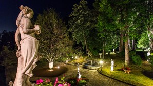 A nighttime garden with statues, a fountain, and well-maintained flower beds. - Villa Turri is a historic mansion near Lucca in the heart of Garfagnana. (Filicaia)