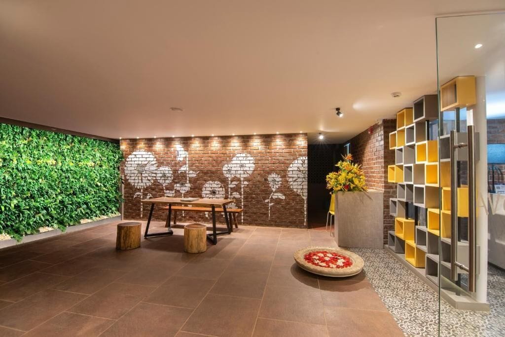 Un intérieur moderne avec un mur de briques, un mur végétal, un coin repas avec une table et des chaises, et un arrangement floral décoratif.