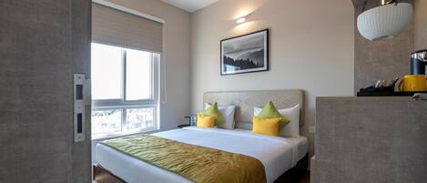 A hotel room with a bed, a window, a ceiling fan, and a painting on the wall.