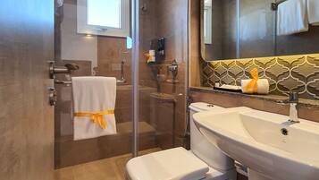 A modern bathroom with a glass-enclosed shower, a white toilet, a sink, and a large mirror.