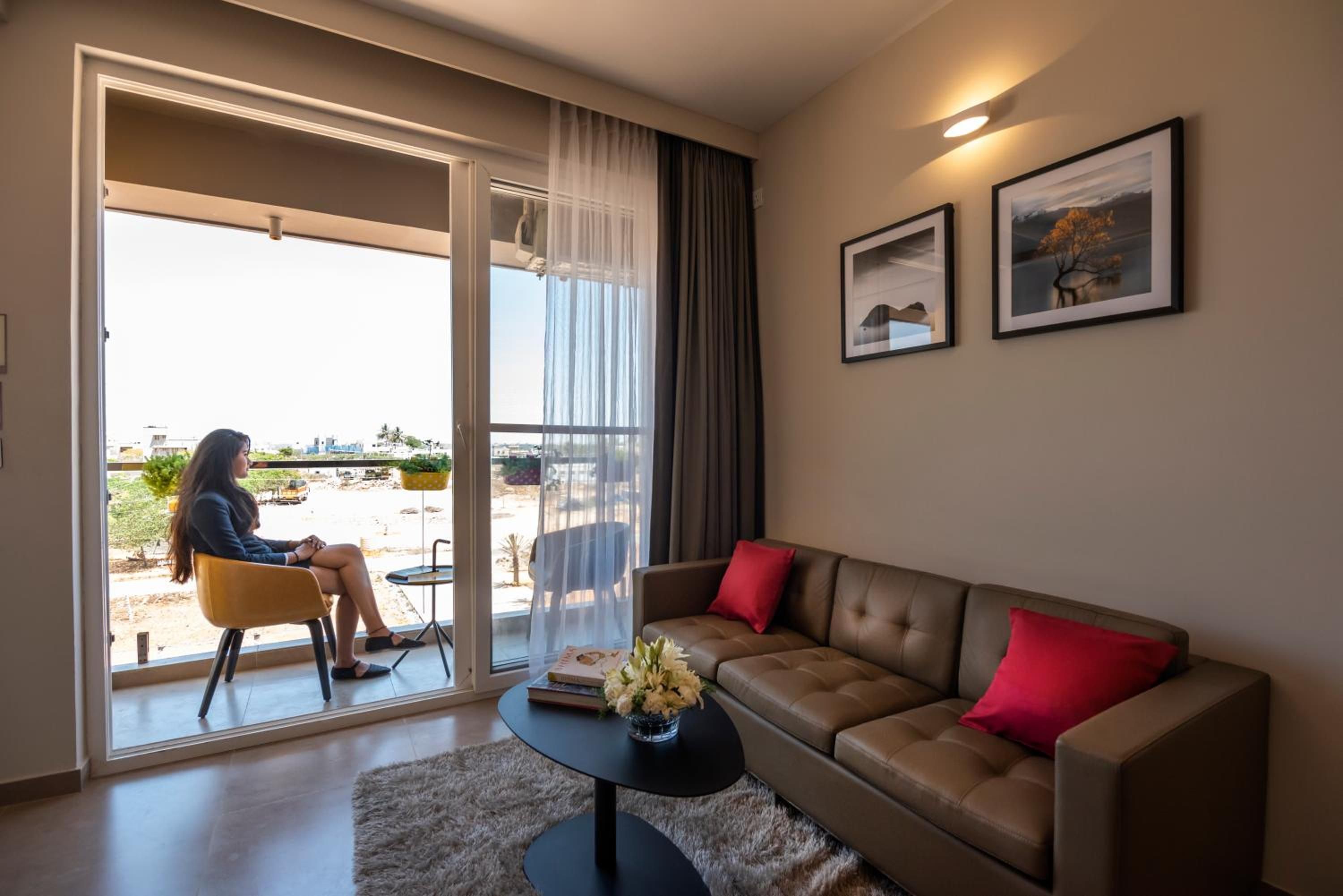 Un salon moderne avec un canapé, une table basse et un fauteuil. Une porte-fenêtre coulissante donne accès à un espace extérieur.