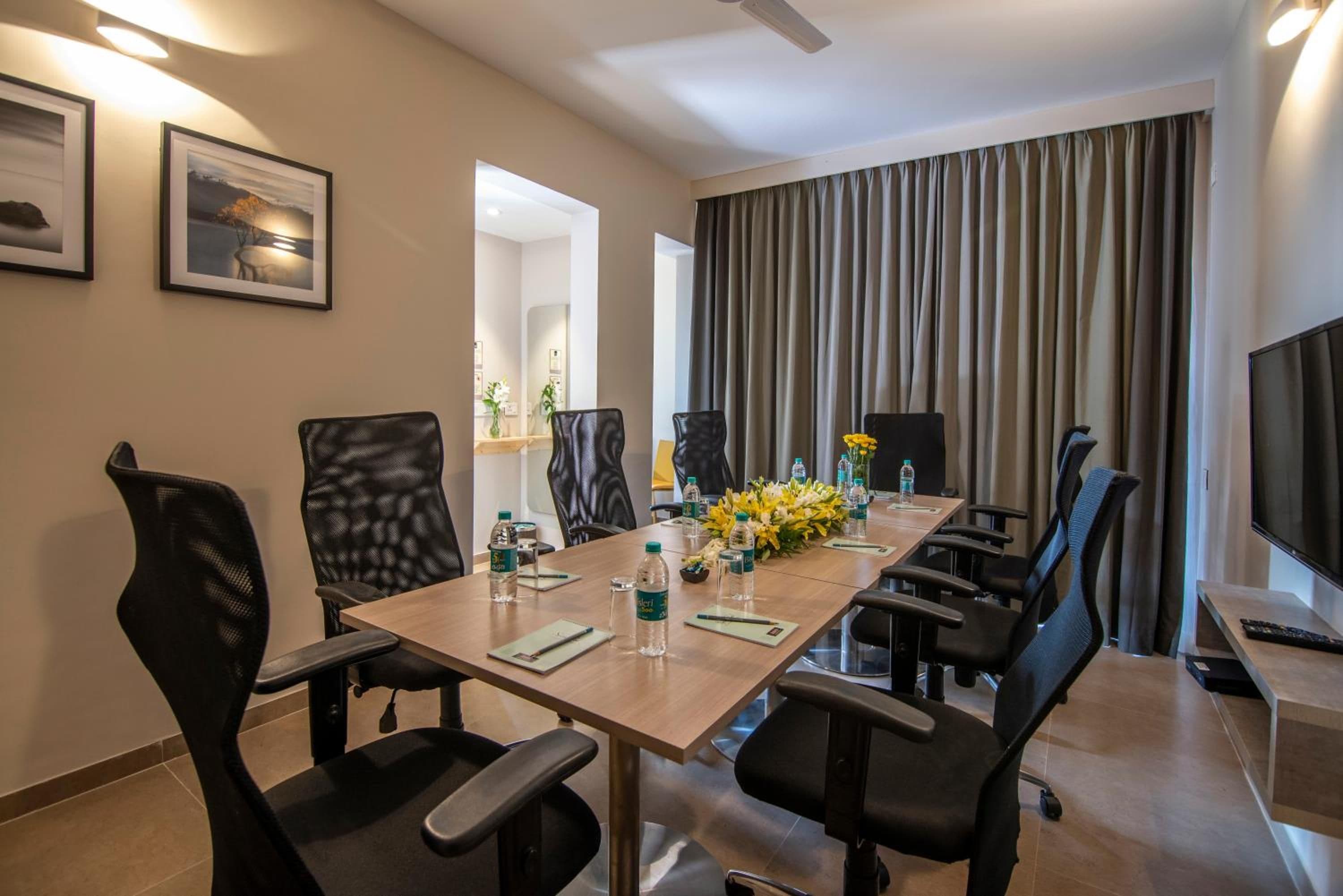 A conference room with a long table, chairs, water bottles, and a bouquet of flowers.