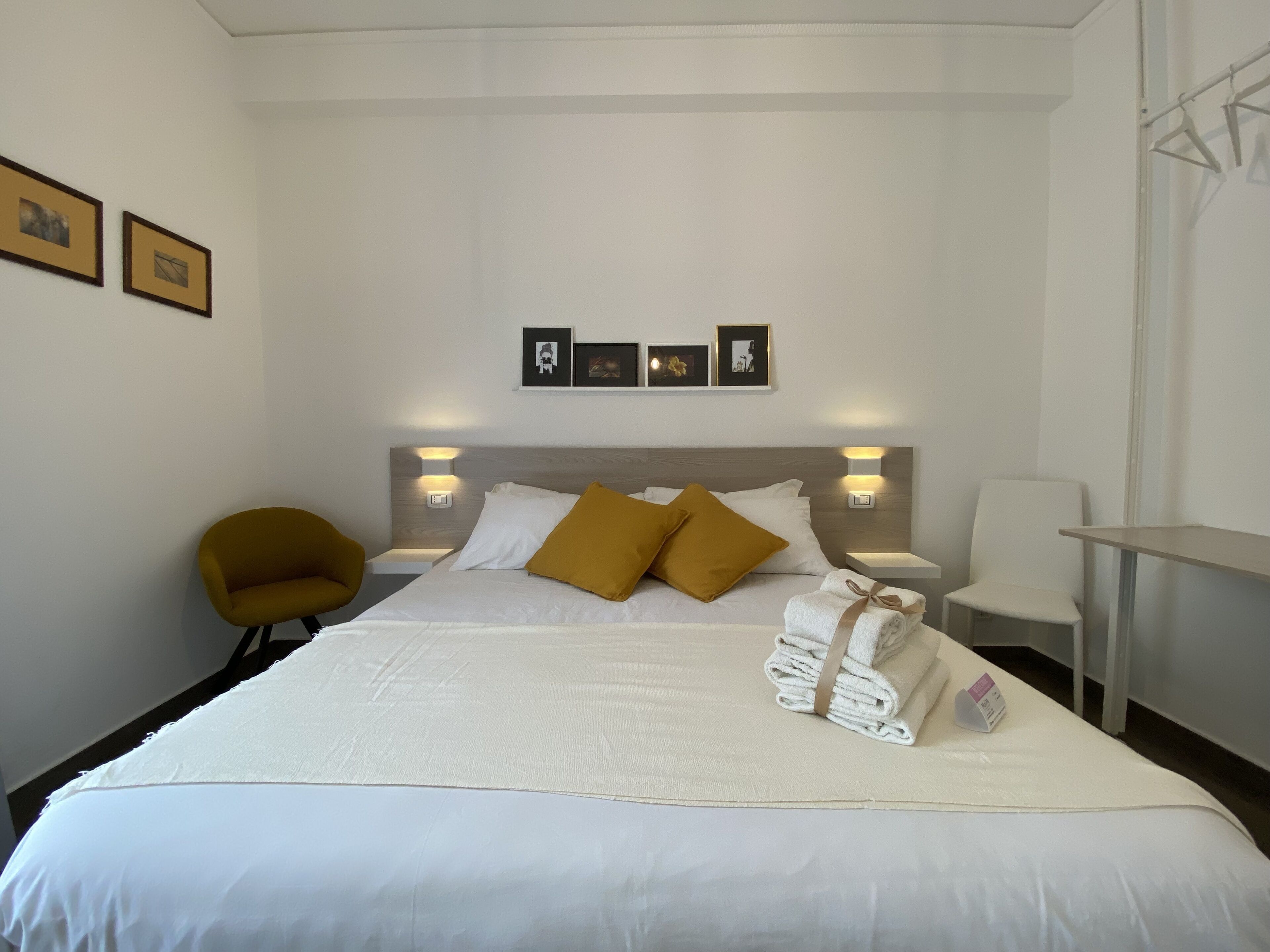 Habitació d'hotel amb un llit gran, dues taules de nit, una cadira i un escriptori.