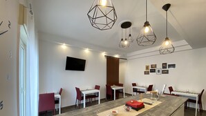A modern dining area with a central island, multiple tables, and hanging pendant lights. - Ma&Mi Light Rooms (Cefalù)