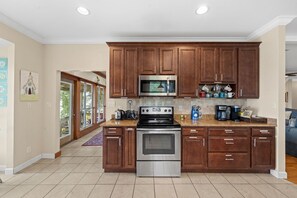 A kitchen with wooden cabinets, stainless steel appliances, and a view to the outside.